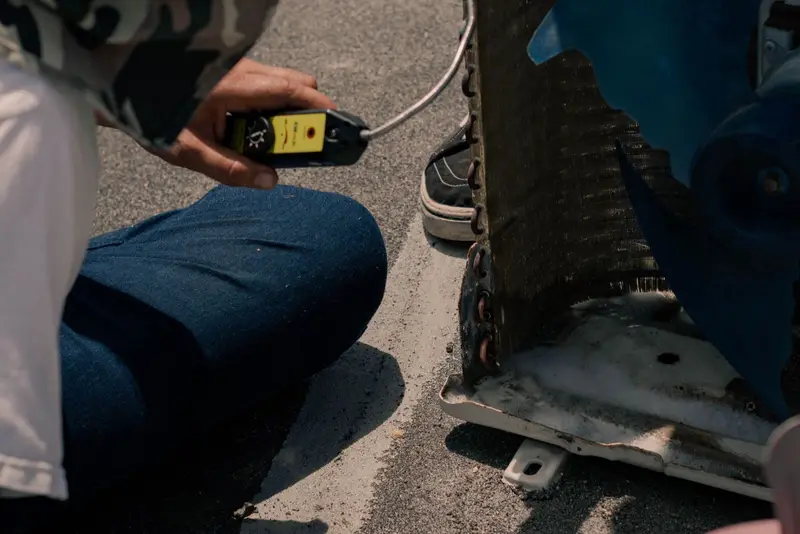 Technician checking an air-conditioning outdoor unit with a leak detector in the sun